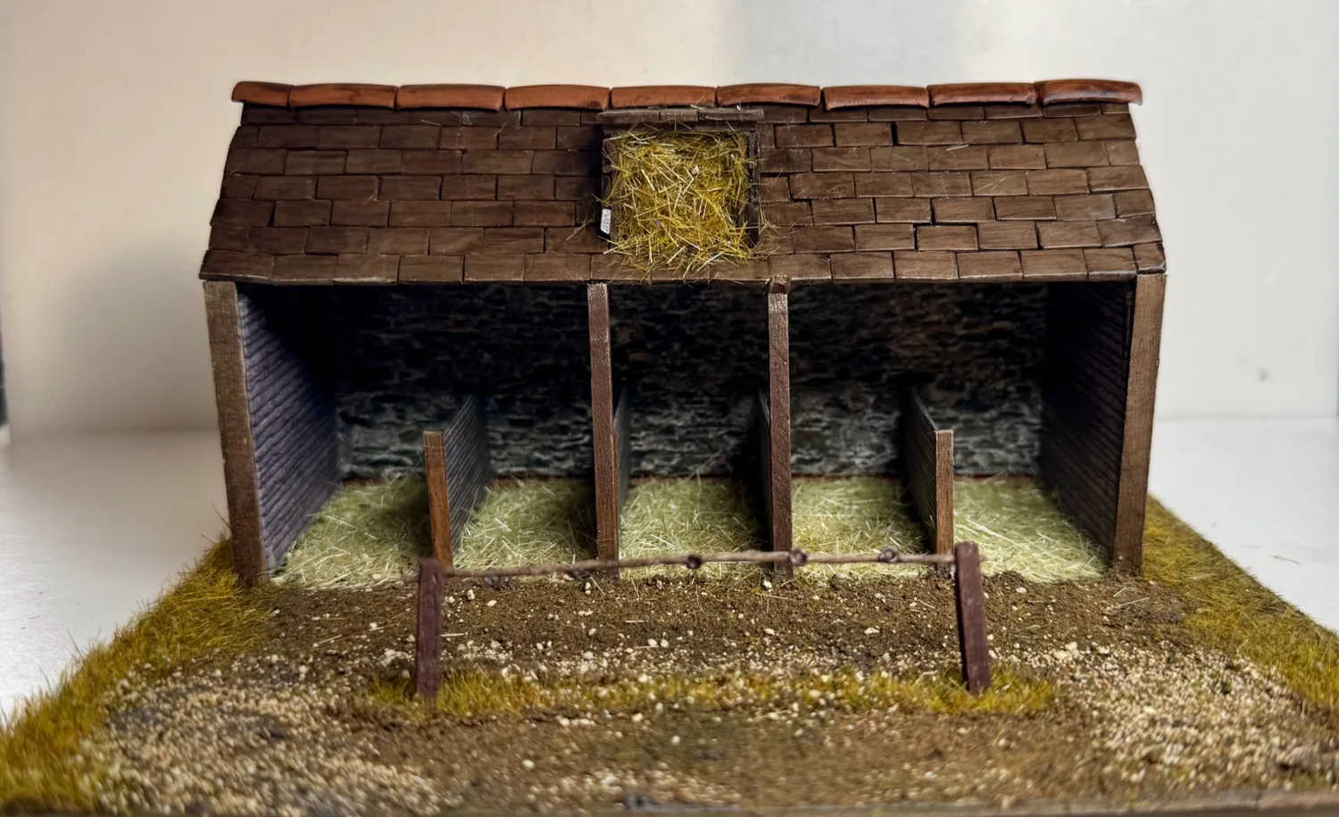 Open-fronted miniature stable with hay and individually tiled roof