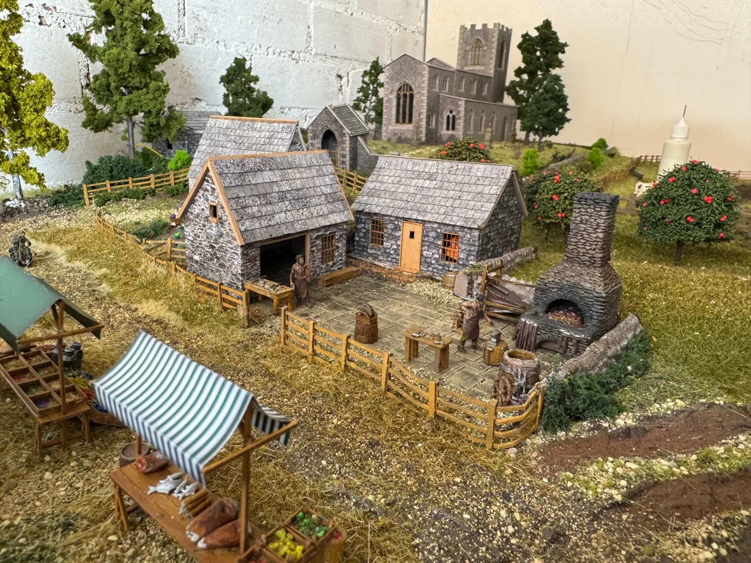 Miniature medieval village scene with church, cottages and blacksmith yard